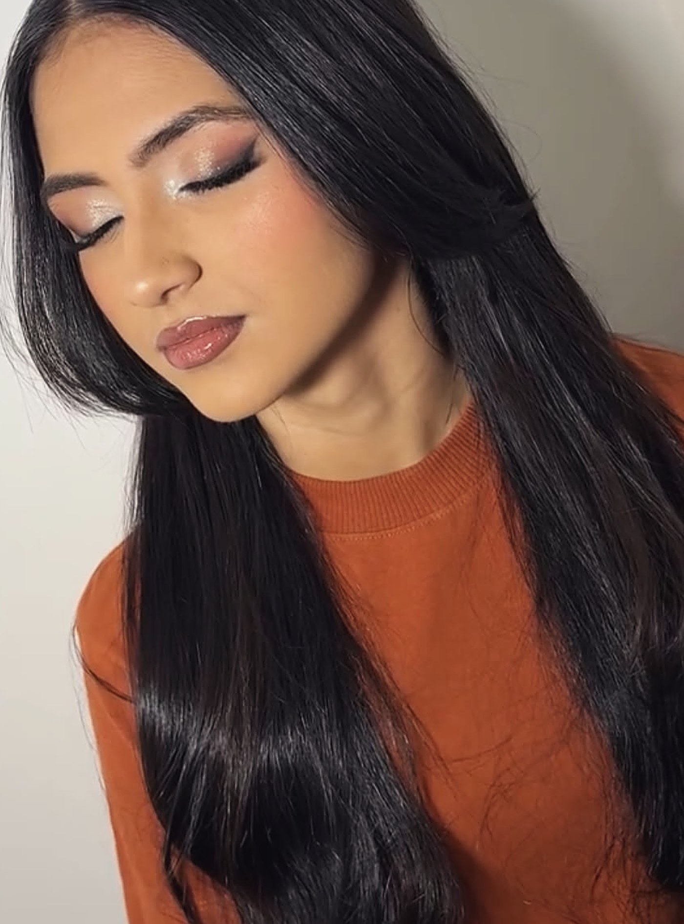 Maquiagem com sombra cintilante e delineado, cliente de olhos fechados